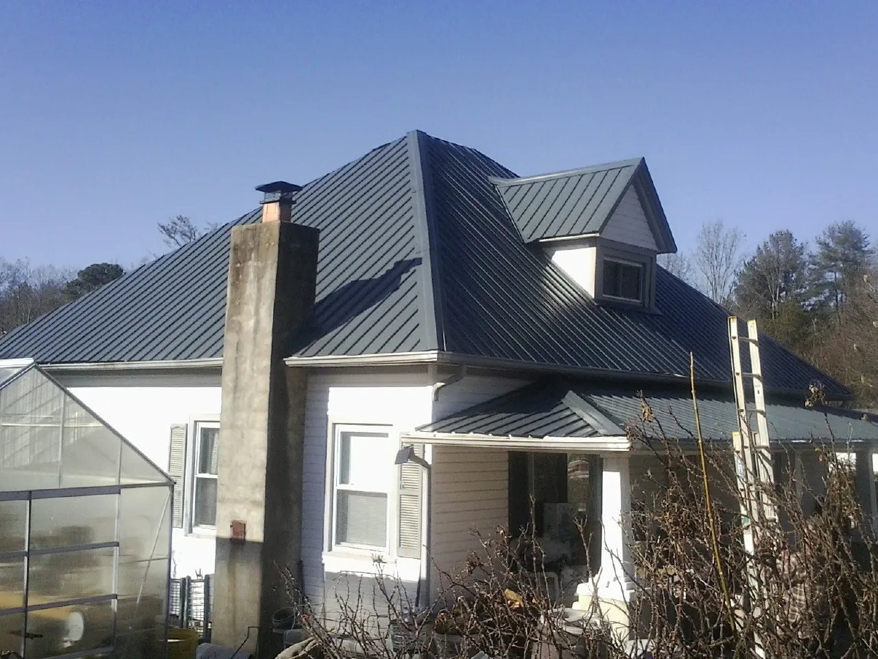 Dark blue standing seam metal roof on a white farmhouse with dormer — Slate & Tile Roof Repair by Roofing Brothers in Putnamville