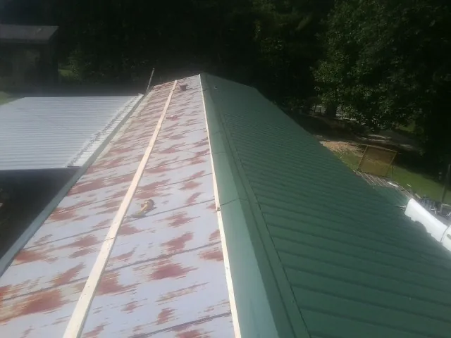 Old rusted panels beside newly installed green metal roofing — Wind Damage Roof Repair by Roofing Brothers in Putnamville