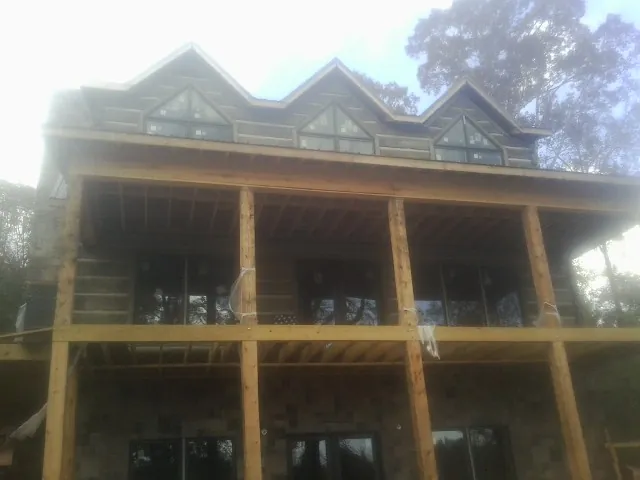 Dormers and porch framing on a large log home under construction — Roof Coating work by our crew in Putnamville
