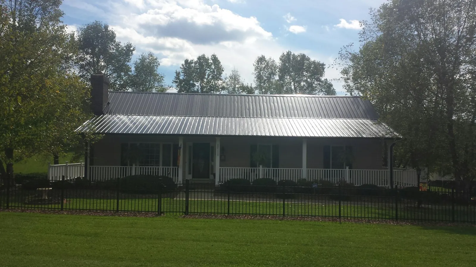 Gray metal roof on a brick ranch with a full width front porch — Gutter Guard Installation work by our crew in Putnamville