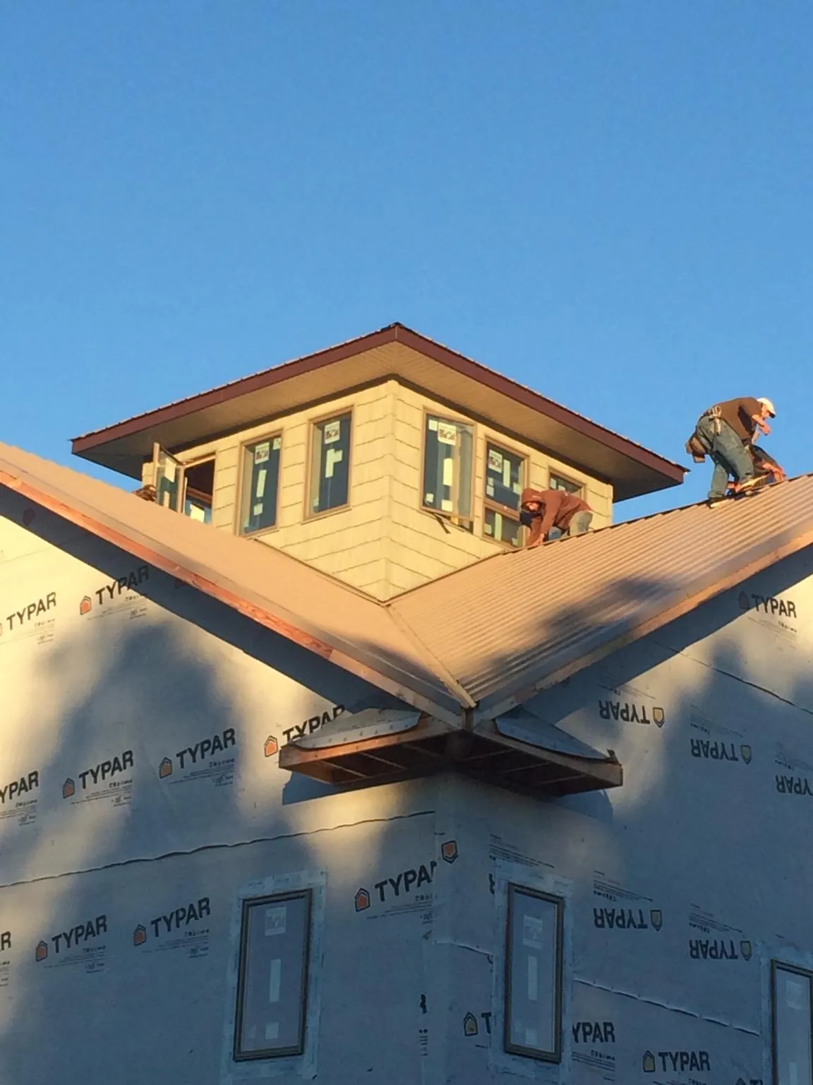 Roofers working around a rooftop cupola on a new metal roof at sunset — Roof Waterproofing in Putnamville by Roofing Brothers
